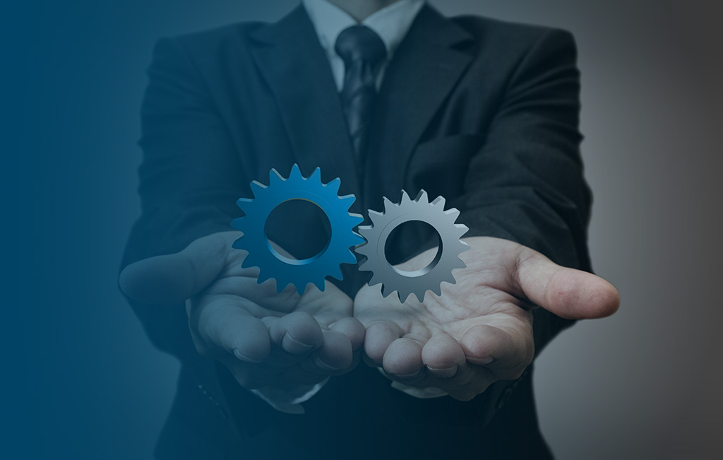 man in suit presenting two blue cogs in hands